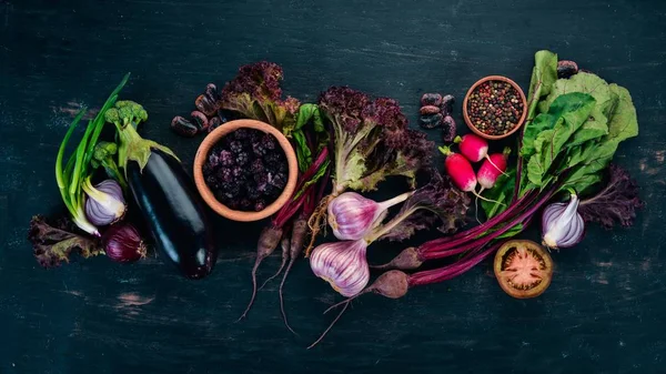 Purple food. Fresh vegetables and berries. On a wooden background. Top view. Copy space.