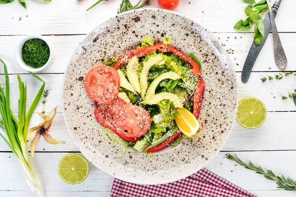 Avokado, domates, taze sebze salatası. Ahşap bir arka plan üzerinde. Üstten görünüm. Kopya alanı.