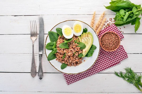 Karabuğday avokado, ıspanak ve haşlanmış yumurta. Ahşap bir arka plan üzerinde. Üstten görünüm. Kopya alanı.