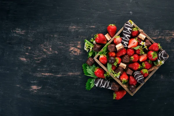 Çilek bir ahşap kutu çikolata ile. Ahşap bir arka plan üzerinde. Üstten görünüm. Kopya alanı.