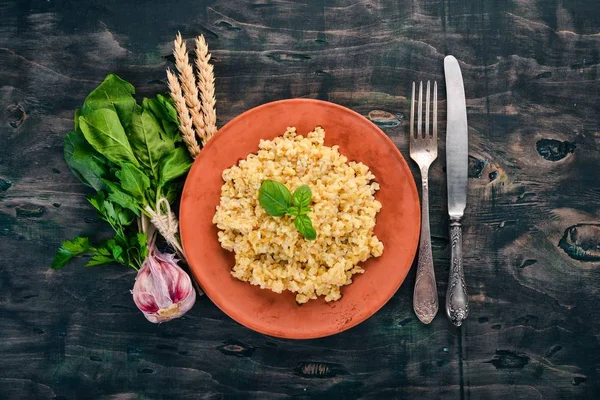Bulgur bir plaka üzerinde Fesleğenli. Ahşap bir arka plan üzerinde. Üstten görünüm. Kopya alanı.