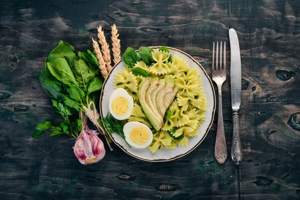 Makarna ıspanak, avokado ve haşlanmış yumurta. Ahşap bir arka plan üzerinde. Üstten görünüm. Kopya alanı.
