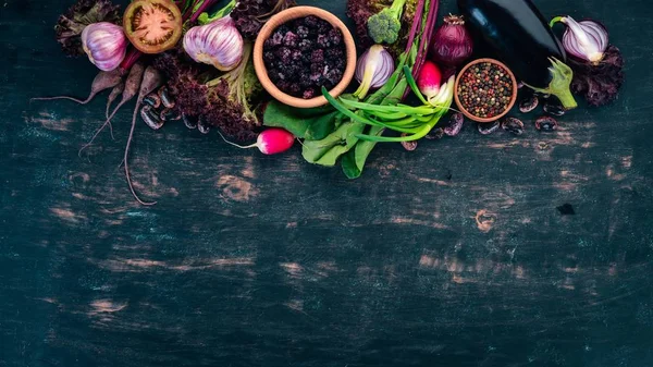 Purple food. Fresh vegetables and berries. On a wooden background. Top view. Copy space.