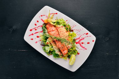 Fırında somon ve sebze salatası. Ahşap bir arka plan üzerinde. Üstten görünüm. Kopya alanı.