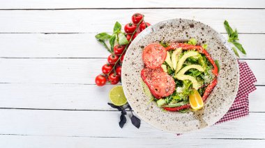 Avokado, domates, taze sebze salatası. Ahşap bir arka plan üzerinde. Üstten görünüm. Kopya alanı.