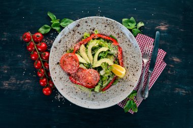 Avokado, domates, taze sebze salatası. Ahşap bir arka plan üzerinde. Üstten görünüm. Kopya alanı.