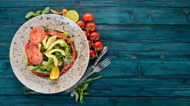 Avokado, domates, taze sebze salatası. Ahşap bir arka plan üzerinde. Üstten görünüm. Kopya alanı.