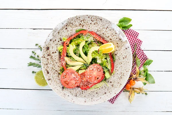 Avokado, domates, taze sebze salatası. Ahşap bir arka plan üzerinde. Üstten görünüm. Kopya alanı.
