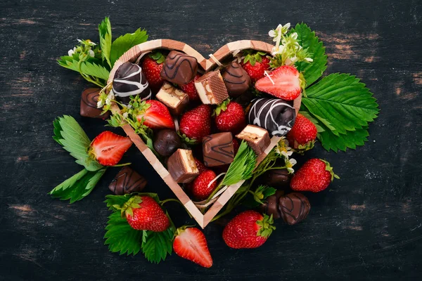 Çilek bir ahşap kutu çikolata ile. Ahşap bir arka plan üzerinde. Üstten görünüm. Kopya alanı.