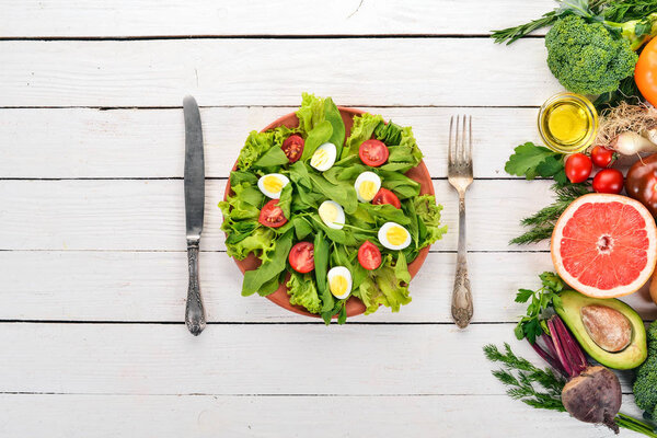 Salad of spinach and quail eggs on a wooden background. Healthy food. Top view. Copy space.
