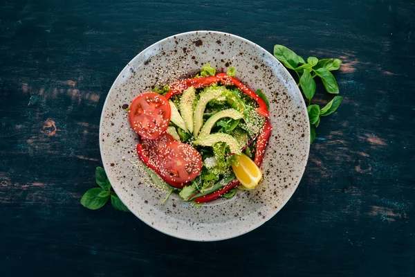 Avokado, domates, taze sebze salatası. Ahşap bir arka plan üzerinde. Üstten görünüm. Kopya alanı.
