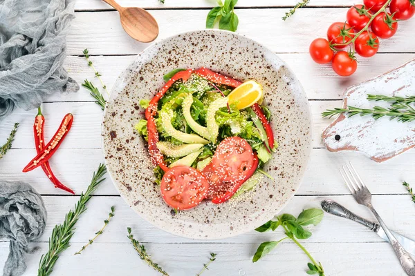 Avokado, domates, taze sebze salatası. Ahşap bir arka plan üzerinde. Üstten görünüm. Kopya alanı.
