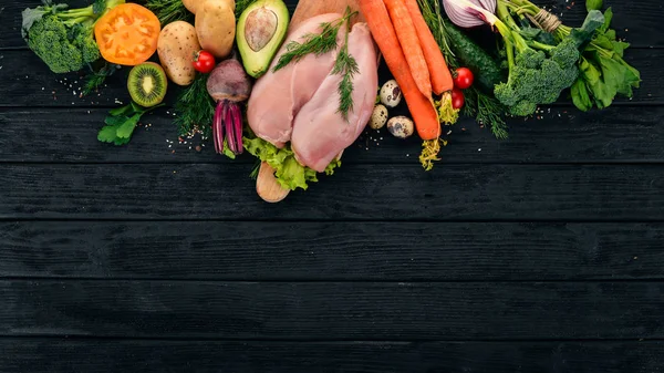 Chicken breast and fresh vegetables. Healthy food. On a black wooden background. Top view. Copy space.