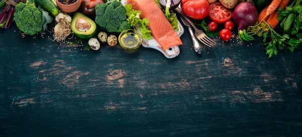 Salmon fillet and fresh vegetables. Healthy food. On a black wooden background. Healthy food. Top view. Copy space.