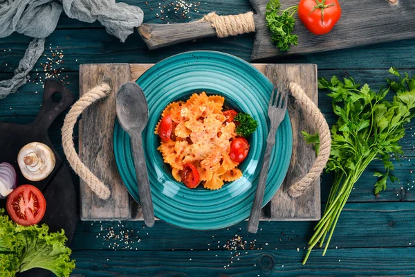 Farfalle makarna domates ve parmesan peyniri. İtalyan mutfağı. Ahşap bir arka plan üzerinde. Üstten görünüm. Kopya alanı.