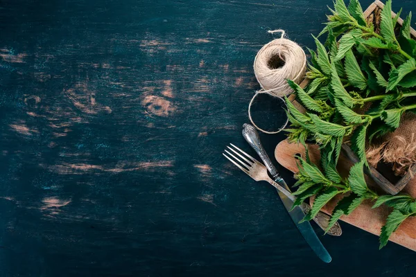 Siyah ahşap zemin taze ısırgan. Üstten görünüm. Kopya alanı.