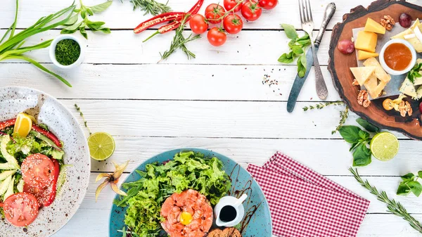 Bir dizi yemek. Tartar, peynir, salata ve sebze. Ahşap bir arka plan üzerinde. Üstten görünüm. Kopya alanı.