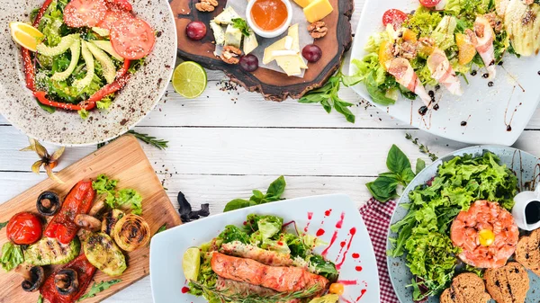 Bir dizi yemek. Tartar, peynir, salata ve sebze. Ahşap bir arka plan üzerinde. Üstten görünüm. Kopya alanı.