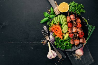 Bir tabak taze sebze ile pişmiş dana eti şiş kebap. Ahşap bir arka plan üzerinde. Üstten görünüm. Kopya alanı.