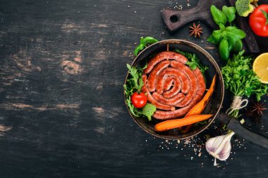 Baharat ile bir tavada kızarmış tavuk sosis. Ahşap bir arka plan üzerinde. Üstten görünüm. Kopya alanı.