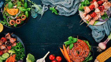 Ürün yelpazesine pişmiş ızgara et. Sosis, şiş, taze sebze. Domates, soğan, sarımsak. Ahşap bir arka plan üzerinde. Kopya alanı.