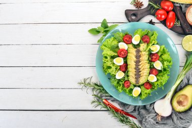 Taze sebze salatası. Avokado, domates, marul, bıldırcın yumurtası. Ahşap bir arka plan üzerinde. Üstten görünüm. Ücretsiz kopya alanı.
