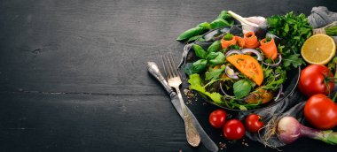 Taze sebze salatası. Roka, domates, havuç, soğan. Ahşap bir arka plan üzerinde. Üstten görünüm. Kopya alanı.