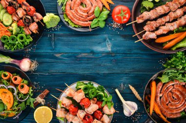 Etler ve taze sebze kümesi. Barbekü, sosis, biftek. Mavi ahşap arka plan üzerinde. Kopya alanı.