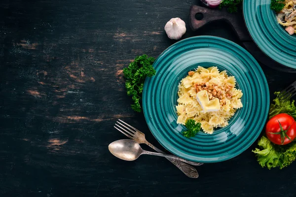 Brie peyniri ve fındık ile farfalle makarna. İtalyan mutfağı. Ahşap bir arka plan üzerinde. Üstten görünüm. Kopya alanı.