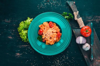 Farfalle makarna domates ve parmesan peyniri. İtalyan mutfağı. Ahşap bir arka plan üzerinde. Üstten görünüm. Kopya alanı.