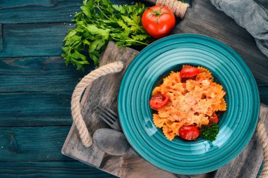 Farfalle makarna domates ve parmesan peyniri. İtalyan mutfağı. Ahşap bir arka plan üzerinde. Üstten görünüm. Kopya alanı.