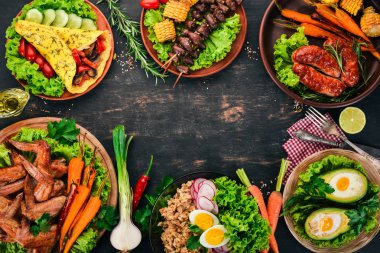 Gıda. Avokado yemekleri, tavuk kanadı, omlet ve barbekü. Ahşap bir arka plan üzerinde. Üstten görünüm. Kopya alanı.