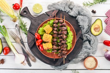 Şiş tavuk kalpler, Mısır ve taze sebze. Ahşap bir arka plan üzerinde. Üstten görünüm. Ücretsiz kopya alanı.