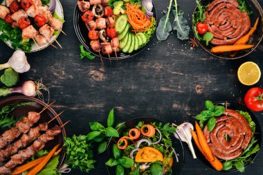 Ürün yelpazesine pişmiş ızgara et. Sosis, şiş, taze sebze. Domates, soğan, sarımsak. Ahşap bir arka plan üzerinde. Kopya alanı.