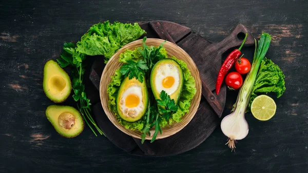 Baked avocado with egg. Healthy food. On a wooden background. Top view. Copy space.