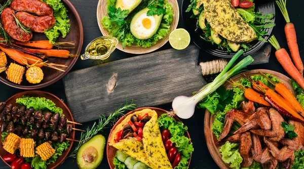 Gıda. Avokado yemekleri, tavuk kanadı, omlet ve barbekü. Ahşap bir arka plan üzerinde. Üstten görünüm. Kopya alanı.