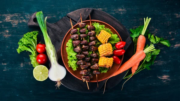 Şiş tavuk kalpler, Mısır ve taze sebze. Ahşap bir arka plan üzerinde. Üstten görünüm. Ücretsiz kopya alanı.