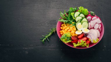 Taze sebze salatası. Mısır, turp, soğan, salatalık, bıldırcın yumurtası. Ahşap bir arka plan üzerinde. Üstten görünüm. Ücretsiz kopya alanı.