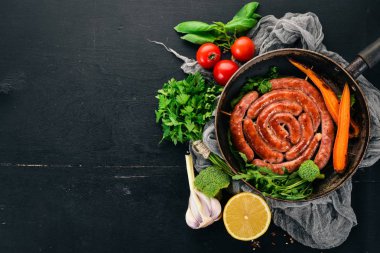 Baharat ile bir tavada kızarmış tavuk sosis. Ahşap bir arka plan üzerinde. Üstten görünüm. Kopya alanı.