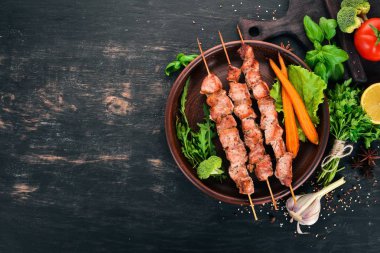 Bir tabakta et pişmiş şiş. Ahşap bir arka plan üzerinde. Üstten görünüm. Kopya alanı.
