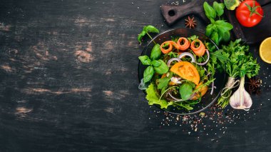Taze sebze salatası. Roka, domates, havuç, soğan. Ahşap bir arka plan üzerinde. Üstten görünüm. Kopya alanı.