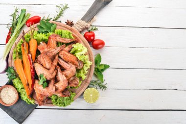 Sebze ve havuç ile ızgara tavuk kanatları. Ahşap bir arka plan üzerinde. Üstten görünüm. Kopya alanı.