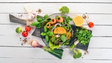 Taze sebze salatası. Roka, domates, havuç, soğan. Ahşap bir arka plan üzerinde. Üstten görünüm. Kopya alanı.