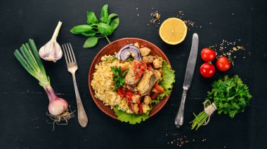 Bulgur with meat, paprika, cherry tomatoes, and vegetables. On a wooden background. Top view. Copy space. clipart