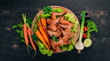 Sebze ve havuç ile ızgara tavuk kanatları. Ahşap bir arka plan üzerinde. Üstten görünüm. Kopya alanı.