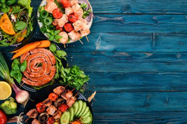 Etler ve taze sebze kümesi. Barbekü, sosis, biftek. Mavi ahşap arka plan üzerinde. Kopya alanı.