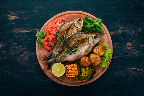 Baked fish with spices and vegetables. Carp On a wooden background. Top view. Copy space.