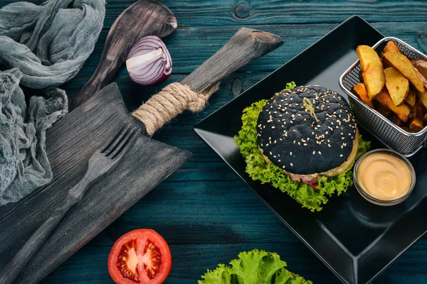 黑汉堡配肉 洋葱和生菜 在一个木质的背景 顶部视图 复制空间 — 图库照片