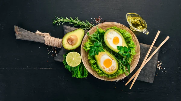Baked avocado with egg. Healthy food. On a wooden background. Top view. Copy space.