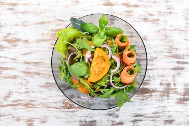 Taze sebze salatası. Roka, domates, havuç, soğan. Ahşap bir arka plan üzerinde. Üstten görünüm. Kopya alanı.